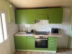 A kitchen with green cabinets, a stainless steel sink, a built-in oven, and a countertop with a kettle and a toaster. - 🌿 Le Cabanon de Cassy - Comfortable gîte with heated pool, near the ocean (Lanton)