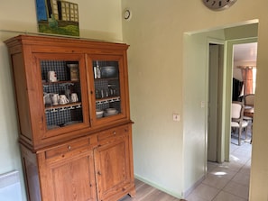 A wooden cabinet with glass doors, a clock on the wall, and a dining area visible through an open door. - 🌿 Le Cabanon de Cassy - Comfortable gîte with heated pool, near the ocean (Lanton)