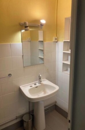 A small bathroom with a white sink, a mirror, and a white toilet.