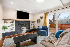 Un salon avec une cheminée, un canapé, une table basse et un téléviseur fixé au mur.