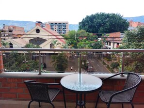 A balcony with two chairs and a table, overlooking a street with buildings and greenery. - Apartment in the heart of the city with views 301 (Medellín)