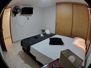 Ein Hotelzimmer mit einem Bett, einem Fernseher, einem Ventilator und einem Kleiderschrank.