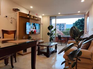 A living room with a TV, a dining table, a sofa, and a balcony with a view. - Apartment in the heart of the city with views 301 (Medellín)