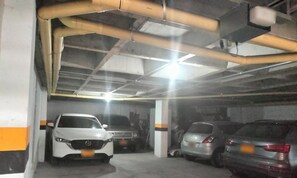 Eine Parkgarage mit mehreren parkenden Autos, Betonpfeilern und Laufstegen.