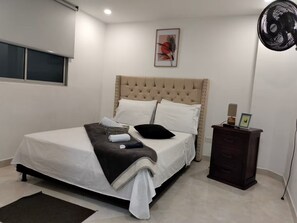 A neatly made bed with a tufted headboard, a bedside table with a lamp, and a framed picture on the wall. - Apartment in the heart of the city with views 301 (Medellín)