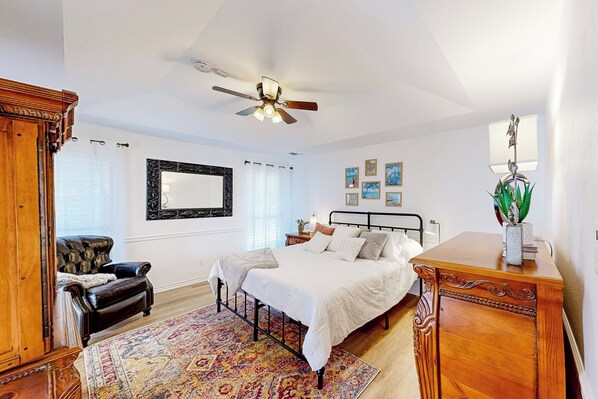 A bedroom with a bed, a ceiling fan, a nightstand, a dresser, a chair, a rug, and a mirror on the wall. - Near Lake & Beach: Welcoming Home w/ Patio (Azle)