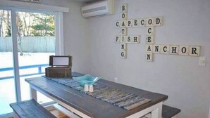 A room with a wooden table, a bowl, and a wall puzzle spelling "CAPE COD ANCHOR". - Private Home Game Room Backyard (Centerville)