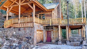 A log cabin with a stone foundation, a wooden balcony, and a stone chimney. - Hot Tub & Mtn Views: Woodsy Cabin in Greer (Greer)