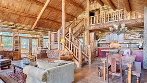 A rustic cabin interior with a wooden staircase, a dining area, and a cozy living room with a sofa and fireplace. - Hot Tub & Mtn Views: Woodsy Cabin in Greer (Greer)