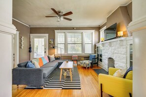 A living room with a gray sofa, yellow armchair, and a fireplace. - 1 Mi to Overton Park: Extended Stay in Memphis! (Memphis)