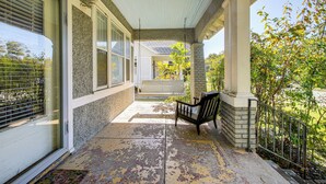 A covered porch with a bench, a door with a glass panel, and a brick wall. - 1 Mi to Overton Park: Extended Stay in Memphis! (Memphis)