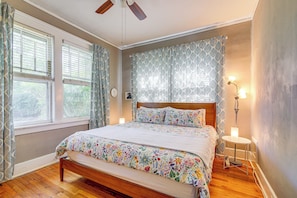 A bedroom with a wooden bed, patterned curtains, a ceiling fan, and a bedside lamp. - 1 Mi to Overton Park: Extended Stay in Memphis! (Memphis)