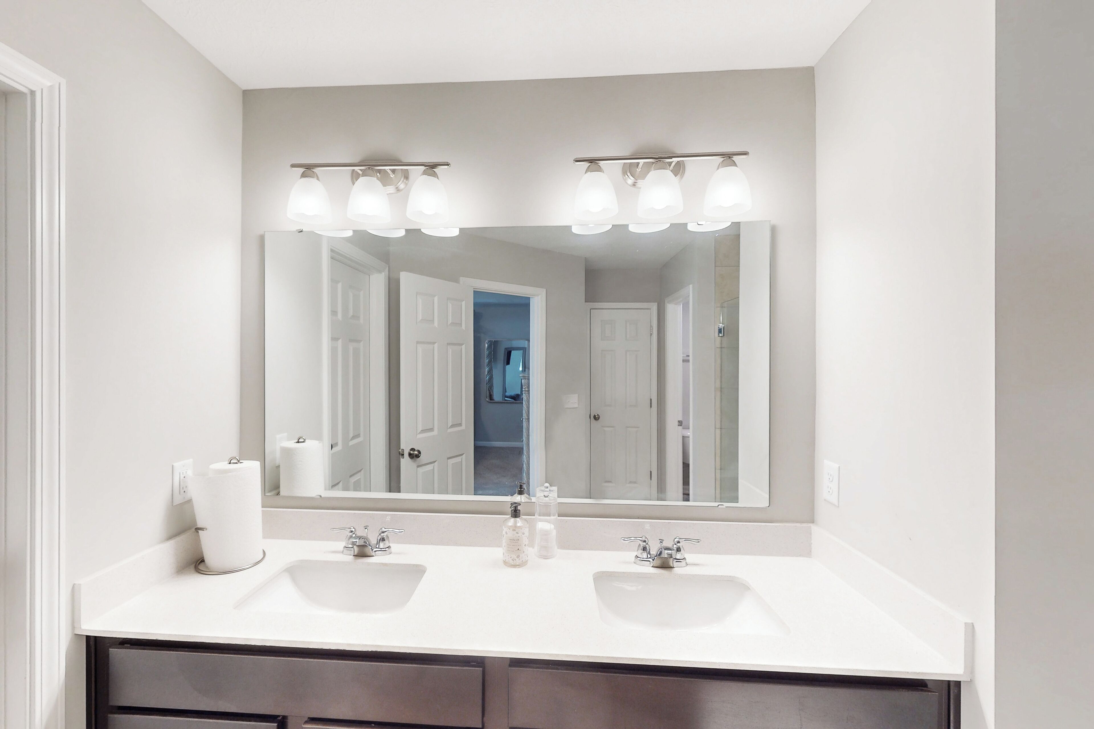 A bathroom with two sinks, a large mirror, and overhead lighting.