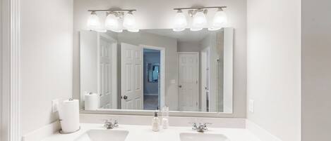 A bathroom with two sinks, a large mirror, and overhead lighting.