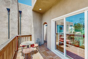 Ein Balkon mit Holzgeländer, einem Tisch und zwei Stühlen.