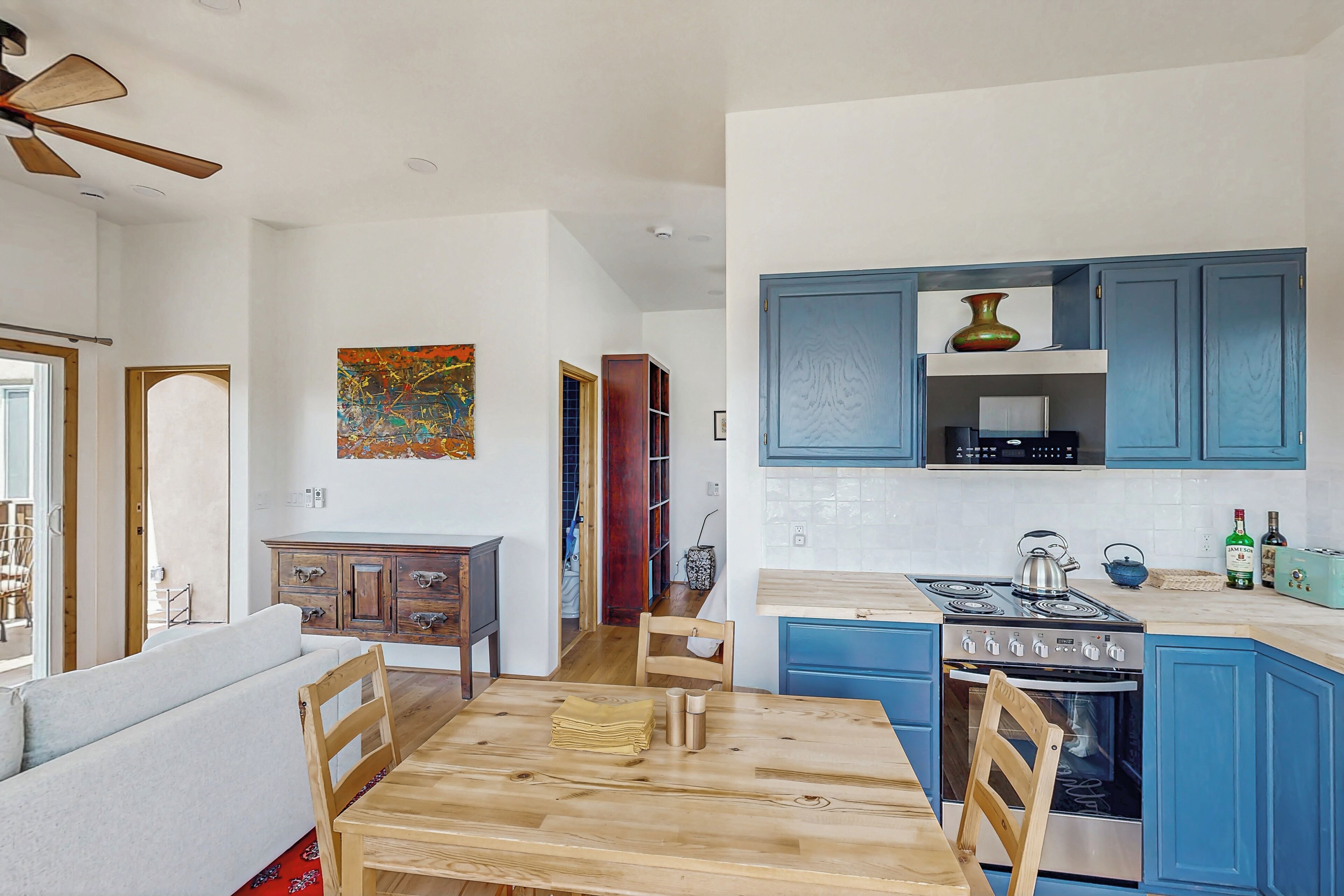 A modern kitchen with blue cabinets, a wooden dining table, and a stove.