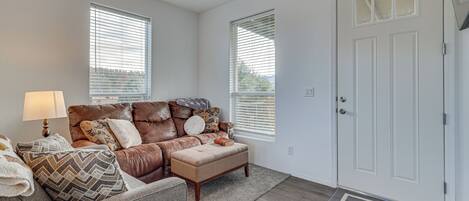 A living room with a brown leather sofa, a wooden coffee table, and a white door.