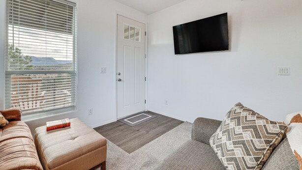 A living room with a sofa, ottoman, and a television on the wall. - Mountain Views & Ponderosa Pines! Arizona Escape (Eagar)