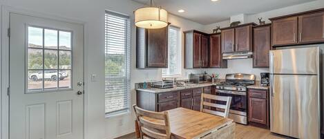 A modern kitchen with wooden cabinets, stainless steel appliances, and a dining area with a wooden table and chairs.