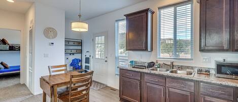 A modern kitchen with wooden cabinets, a built-in oven, and a large window.