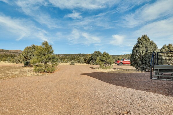 A gravel driveway leading to a building with a red vehicle parked nearby. - Mountain Views & Ponderosa Pines! Arizona Escape (Eagar)