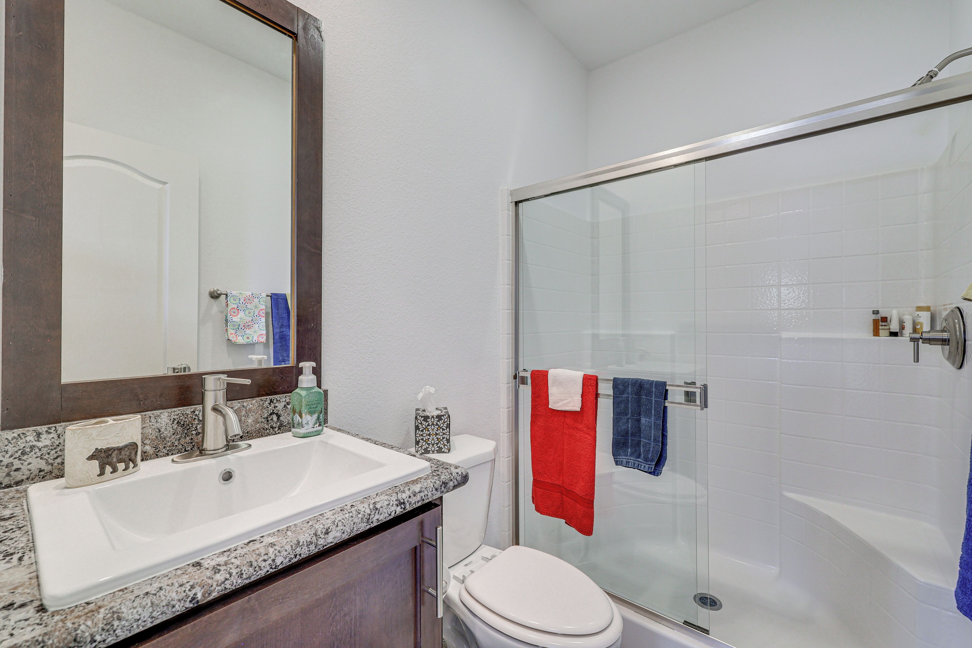 A bathroom with a white sink, a mirror, a toilet, and a glass-enclosed shower.