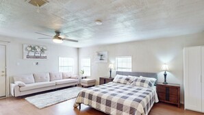 A bedroom with a bed, a sofa, a ceiling fan, and a nightstand. - 4BR w/ Pool Table & WFH Desk, Near Fishing Pond (Quinlan)