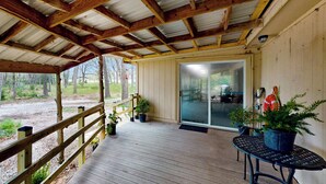 A covered porch with wooden beams, a table, and potted plants. - 4BR w/ Pool Table & WFH Desk, Near Fishing Pond (Quinlan)