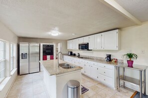 A modern kitchen with white cabinets, stainless steel appliances, and a granite countertop. - 4BR w/ Pool Table & WFH Desk, Near Fishing Pond (Quinlan)