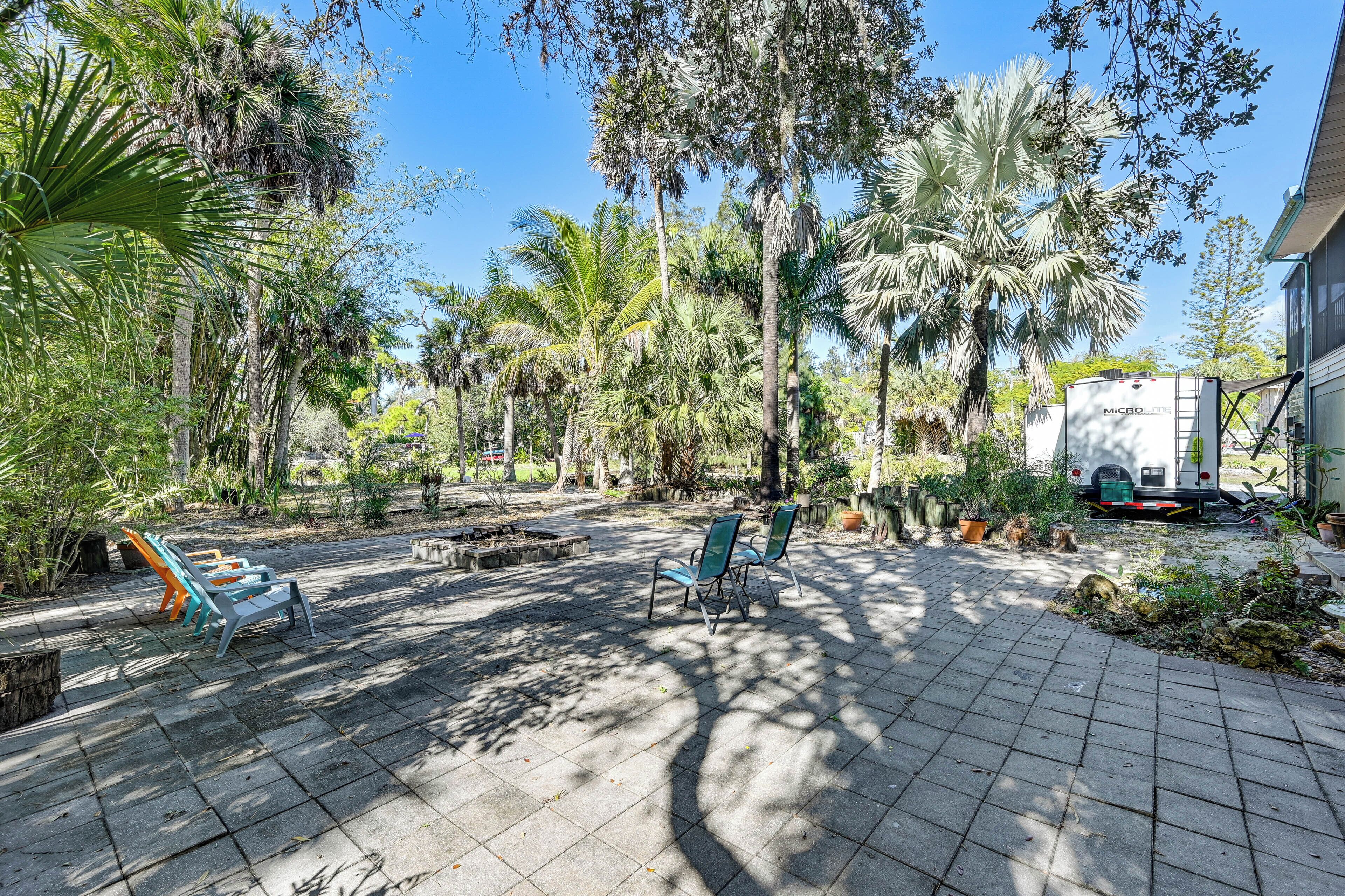 A paved patio with outdoor seating, surrounded by palm trees and greenery.