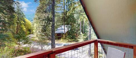 A balcony with a view of a forest and a road.