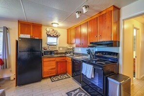 A kitchen with wooden cabinets, a black refrigerator, a microwave, a stove, and a dishwasher. - 6 Mi to Dtwn Denver: Artsy Home w/ Mtn Views! (Denver)