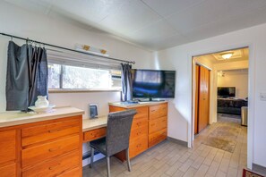 A compact room with a wooden desk, a chair, a television, and a window with curtains. - 6 Mi to Dtwn Denver: Artsy Home w/ Mtn Views! (Denver)