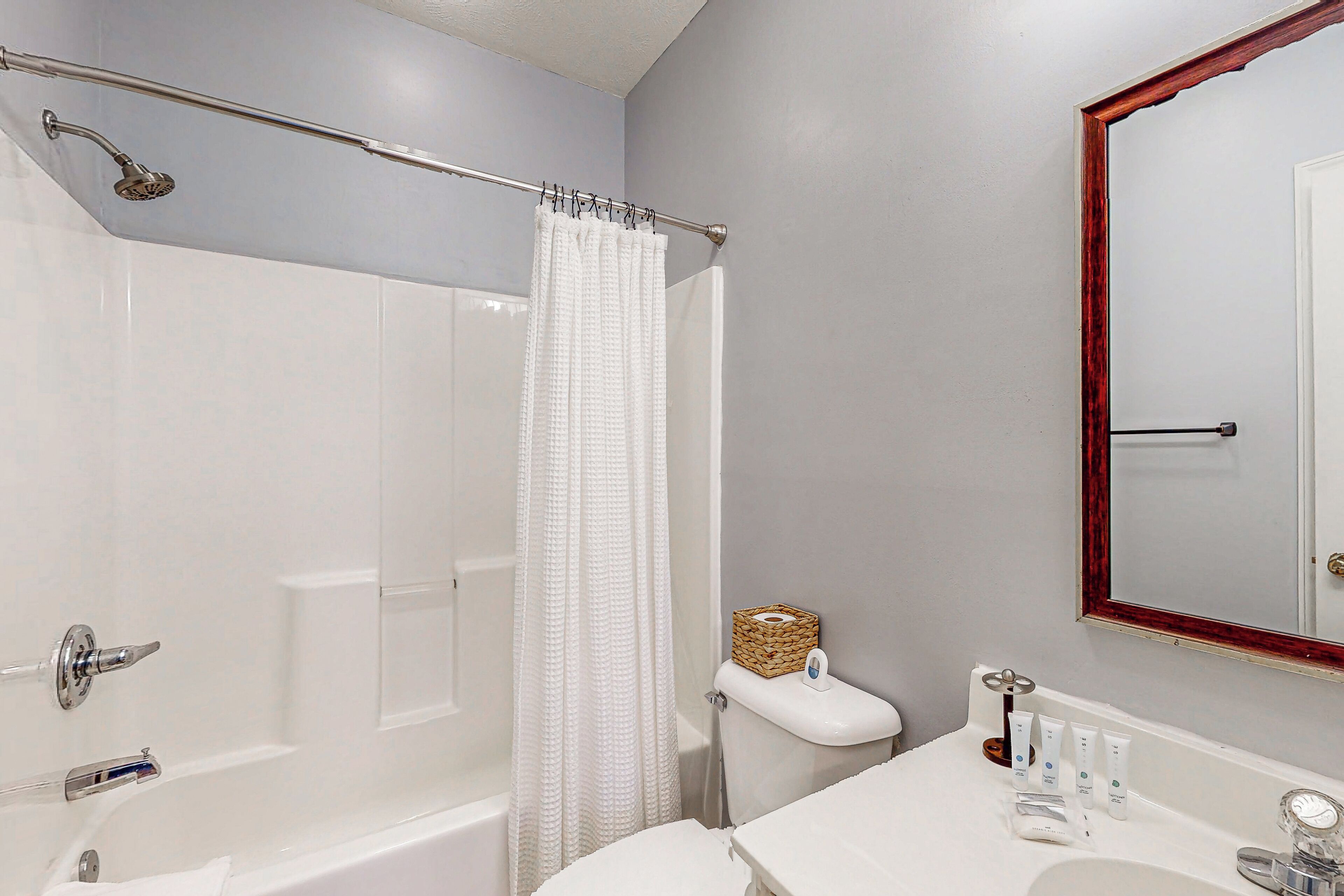 A bathroom with a bathtub, shower, and a vanity with a mirror.