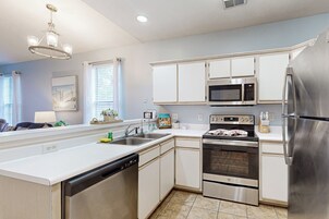 Una cocina moderna con armarios blancos, electrodomésticos de acero inoxidable, lavavajillas y una isla grande.