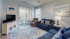 Ein Wohnzimmer mit Fernseher, Sofa, Sessel und Deckenventilator.