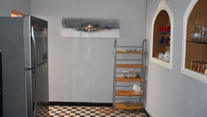 Una cocina con un refrigerador, una estantería metálica y un piso a cuadros.