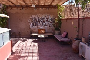 An outdoor patio with a seating area, a table, and a potted plant. - Zagora Berber Guest House Riad (Zagora)