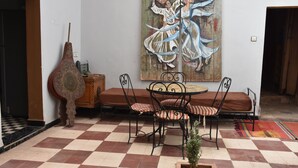 Un comedor con suelo a cuadros, una mesa redonda con sillas y un cuadro grande en la pared.