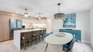 Una cucina moderna con isola centrale, sgabelli da bar e un tavolo da pranzo con sedie.