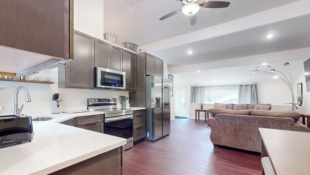A modern kitchen with stainless steel appliances, a dining area with a table and chairs, and a living room with a sofa. - Beautiful Stucco House in North Hudson (Hudson)