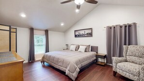 A bedroom with a bed, a desk, a chair, a ceiling fan, and a window with curtains. - Beautiful Stucco House in North Hudson (Hudson)