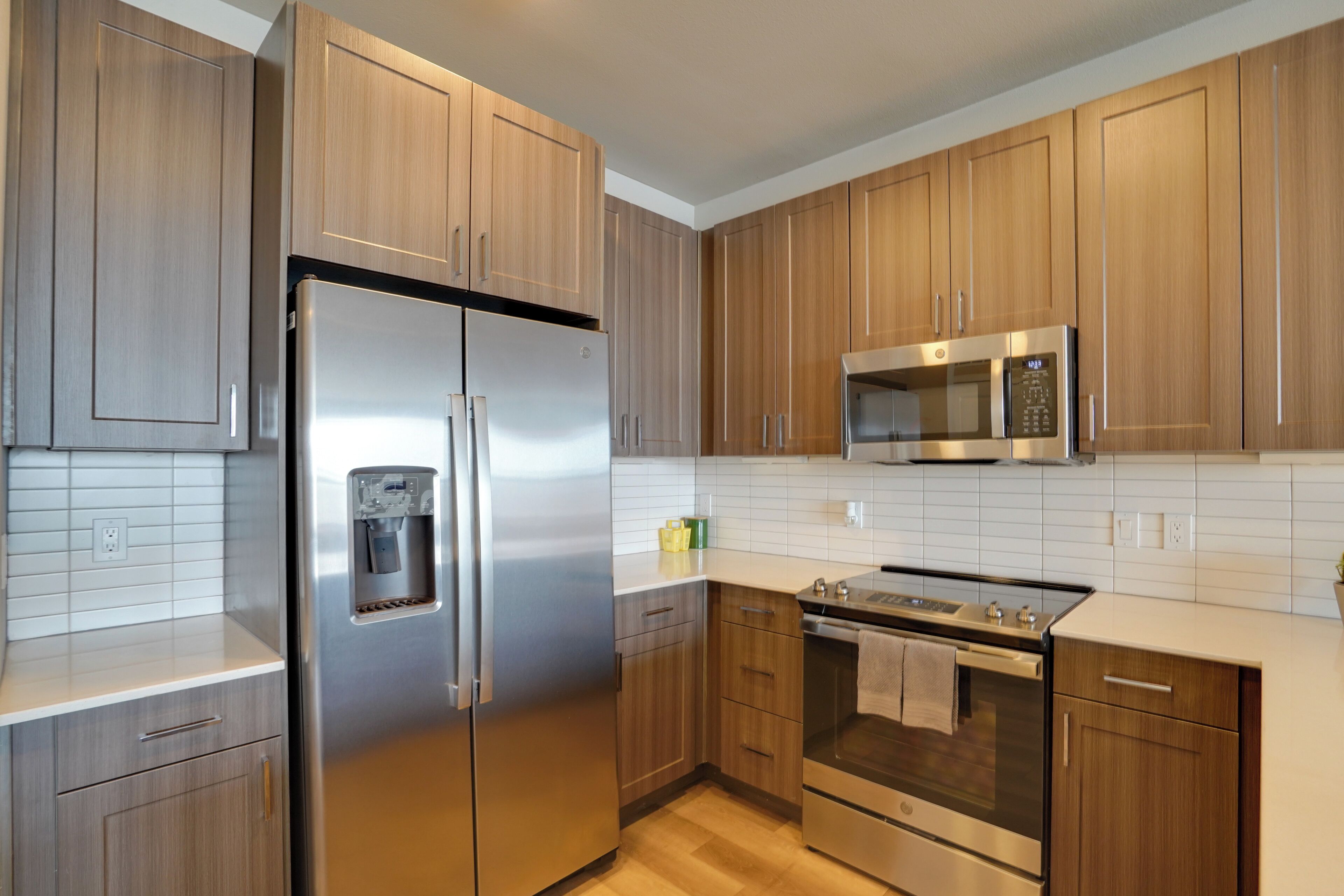 A modern kitchen with wooden cabinets, stainless steel appliances, and a white tiled backsplash.