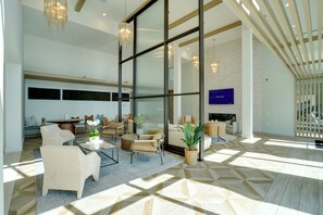A spacious living area with a large window, a flat-screen TV, and a modern chandelier. - Pool Access! Luxe Condo 7 Mi to Coquina Beach (Bradenton)