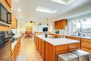 A modern kitchen with wooden cabinets, a large island, and a dining area with chairs and a table. - Horse-friendly Home w/ Patio in Prescott! (Prescott)