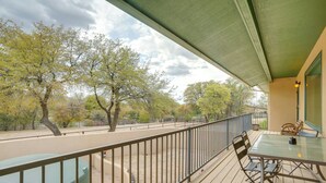 Ein Balkon mit Tisch und Stühlen, Blick auf Bäume und einem Geländer.