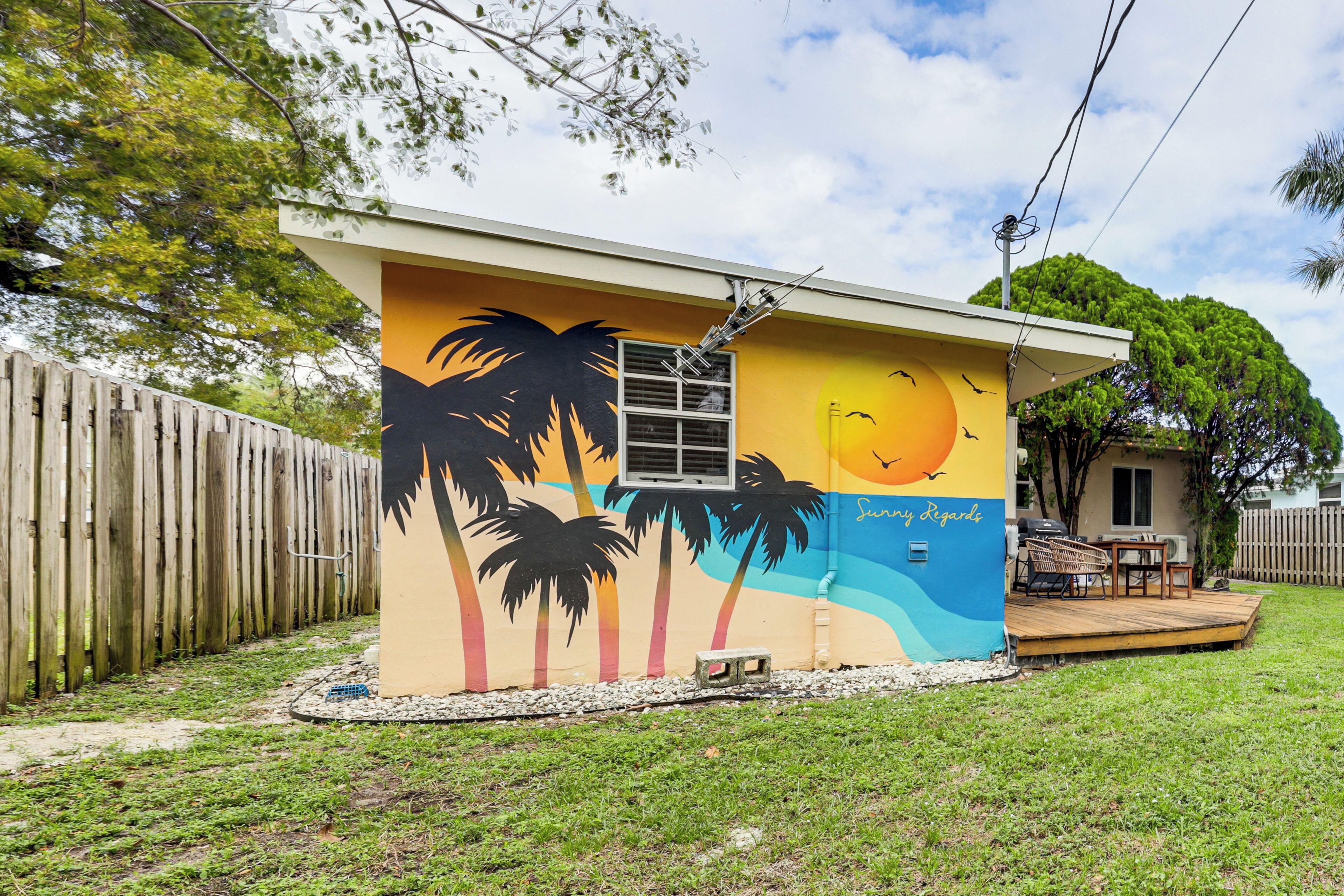 A house with a mural of palm trees and a sunset.