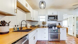 A modern kitchen with white cabinets, a stainless steel microwave, and a dishwasher. - 5 Mi to Las Olas Beach! Bright Home w/ Fenced Yard (Fort Lauderdale)