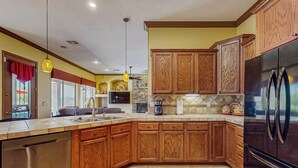 A kitchen with wooden cabinets, a stainless steel refrigerator, and a built-in dishwasher. - Goodyear Home w/ Private Pool, Spa & Built-in BBQ (Goodyear)