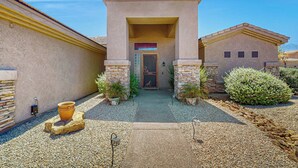 A building entrance with a stone facade, a door, and potted plants. - Goodyear Home w/ Private Pool, Spa & Built-in BBQ (Goodyear)